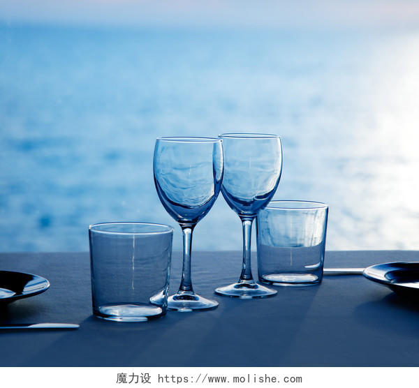 蓝色的大海边桌子上的玻璃杯和盘子